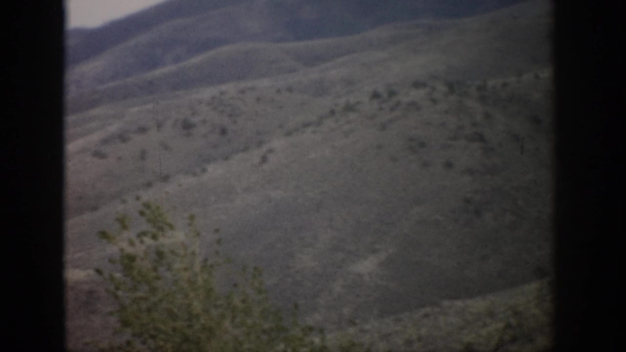 1959 Colorado 8mm frame showing muted rolling hills and scrub vegetation through a dark window-like border.