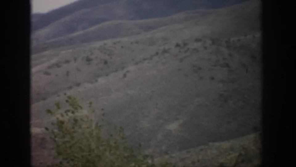 1959 Colorado 8mm frame showing muted rolling hills and scrub vegetation through a dark window-like border.
