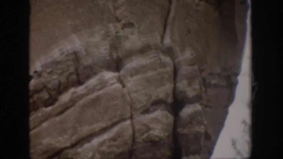 1959 Colorado 8mm frame showing blurred, layered rock formations and a bright gap between stone walls.