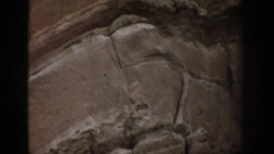 1959 Colorado 8mm frame showing a close, textured rock surface with rounded strata and visible film-edge darkness.