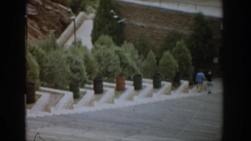 Colorado tourist viewpoint with concrete steps, green shrubs, lampposts, and two distant visitors walking along the path.