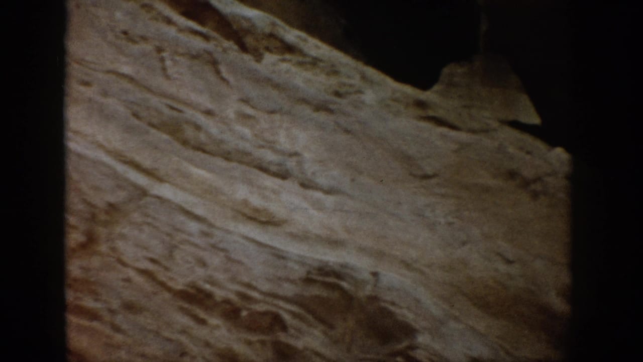 Close view of a layered rock surface with a dark opening near the top.