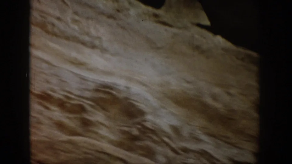1959 Colorado 8mm close-up of pale layered rock, eroded ridges, and a shadowed opening at the edge of the frame.