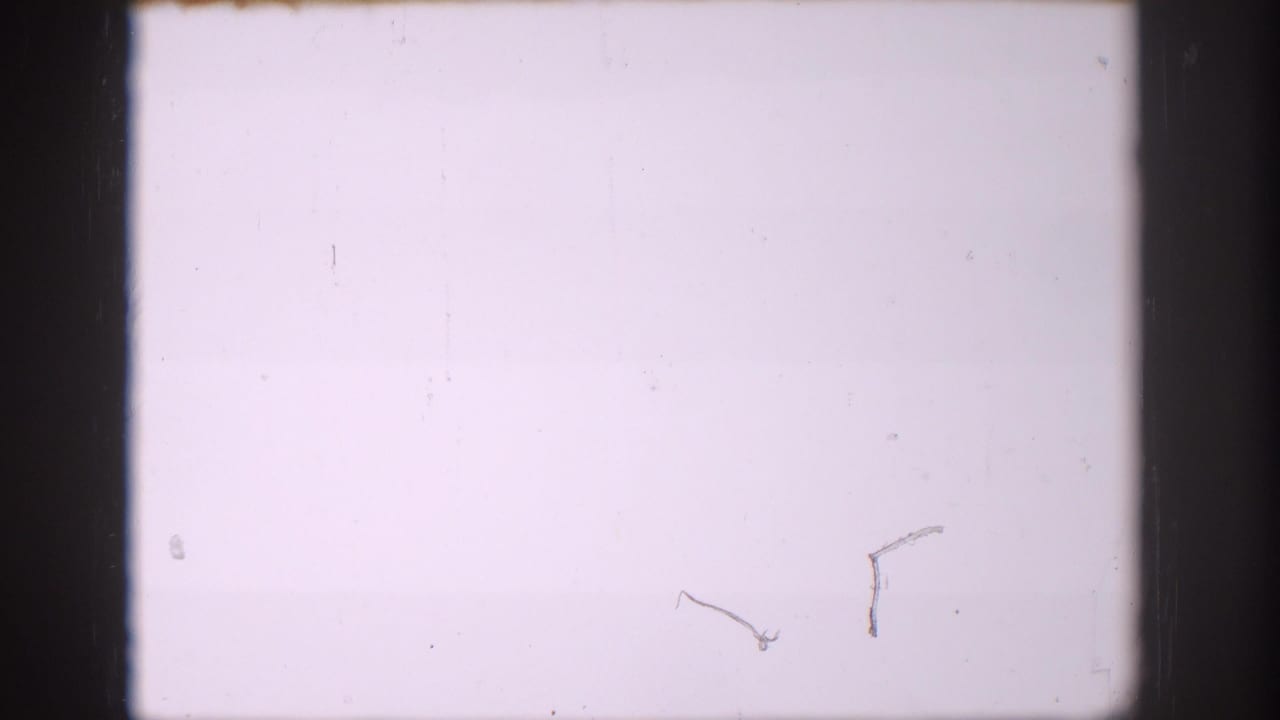 A pale 8mm frame with dark gate edges and tiny surface marks, likely preceding the sign detail in the Colorado home-movie clip.