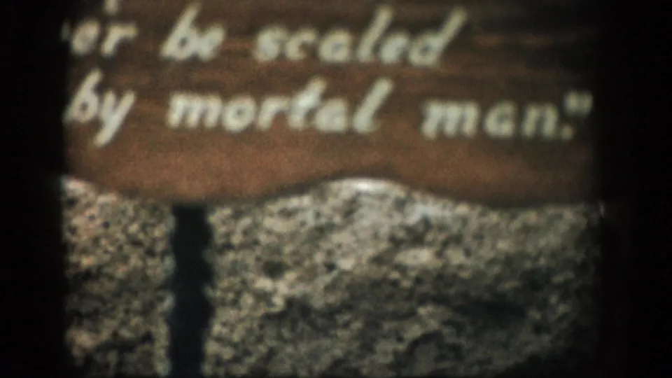 Final close view of the 1959 Colorado sign, with the words “be scaled by mortal men” visible over a rugged rock surface.