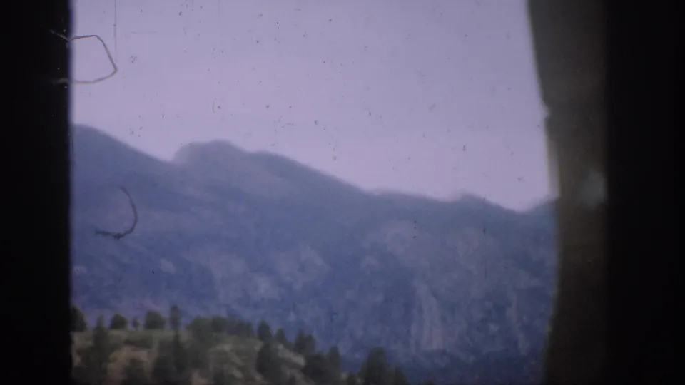 1959 Colorado home-movie view of distant mountains, a tree line, hazy sky, and visible 8mm film wear.