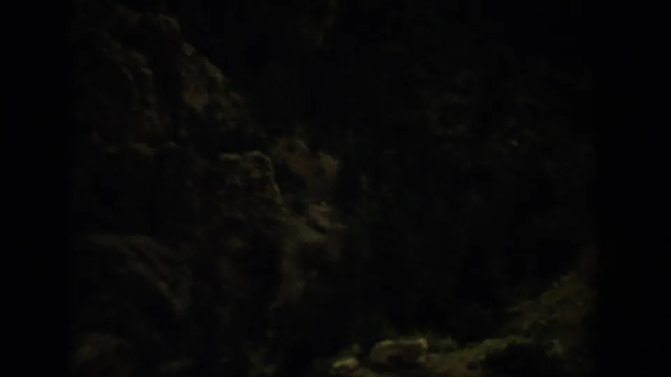 Dark 1959 Colorado 8mm frame with underexposed wooded landforms and shadowed hillside texture near the end of the clip.