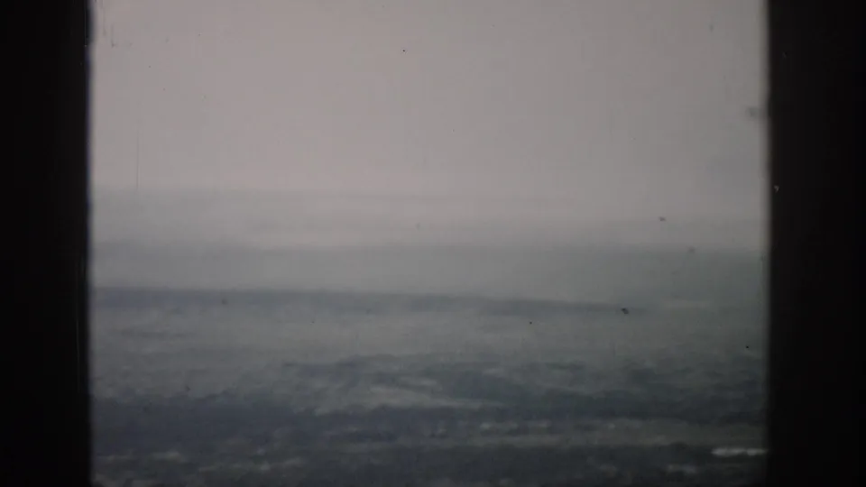 1959 Colorado 8mm frame showing a muted aerial landscape through an airplane window with dust and soft film grain.