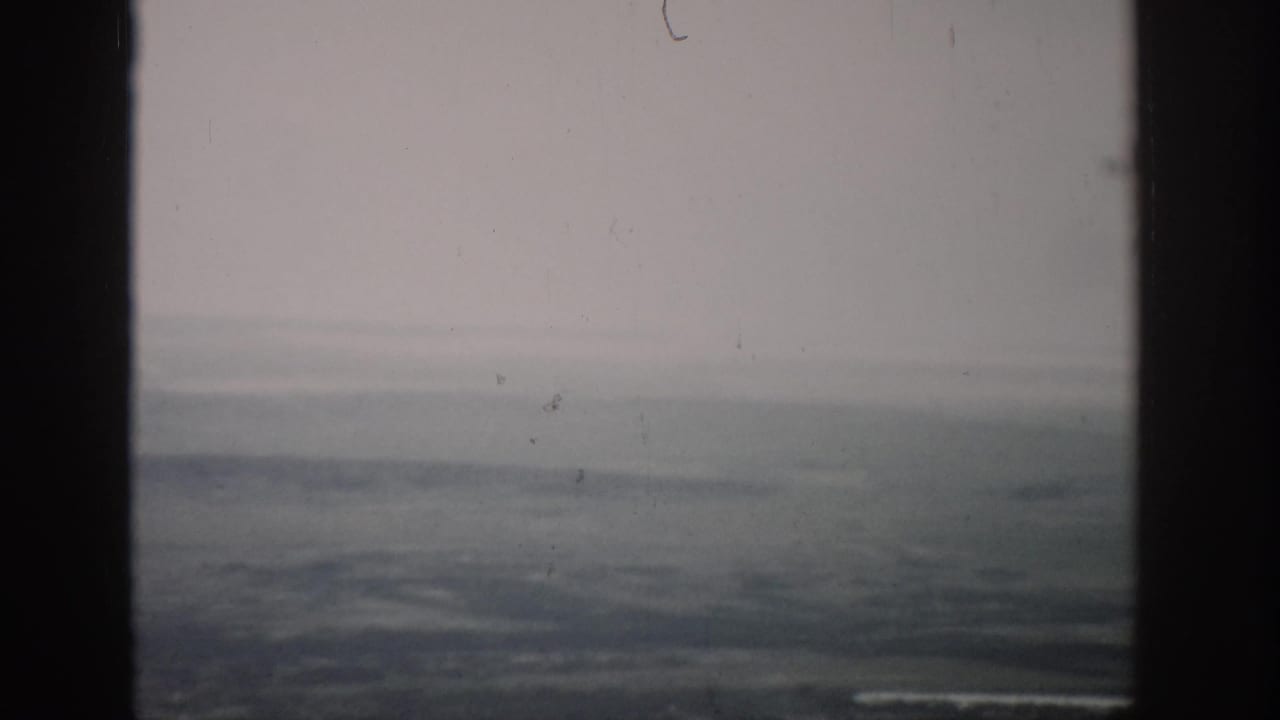 A soft 1959 Colorado aerial view appears beyond dark aircraft-window dividers, with a low horizon and faded color.