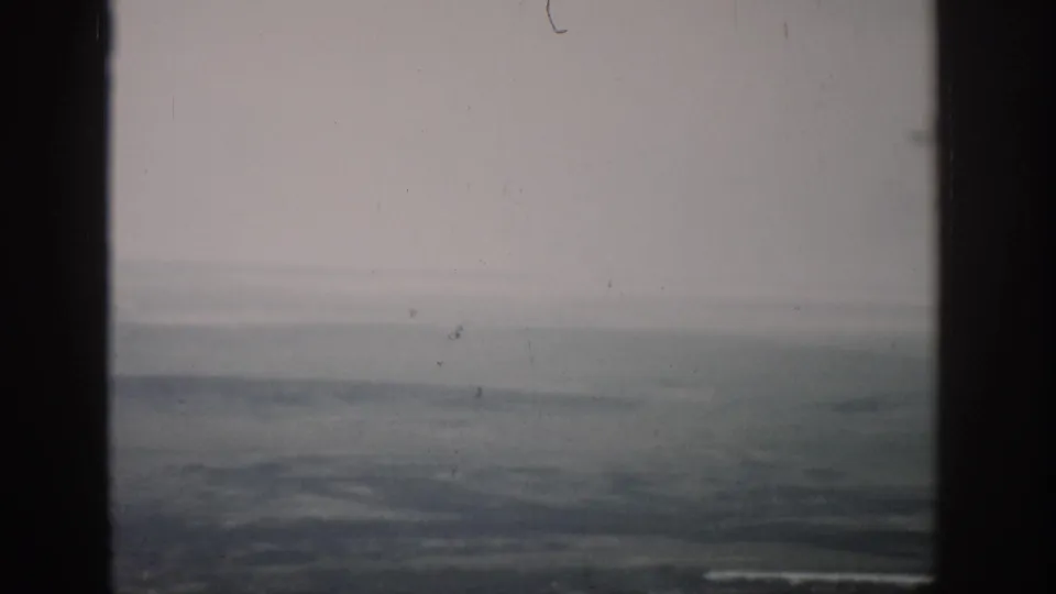 A soft 1959 Colorado aerial view appears beyond dark aircraft-window dividers, with a low horizon and faded color.