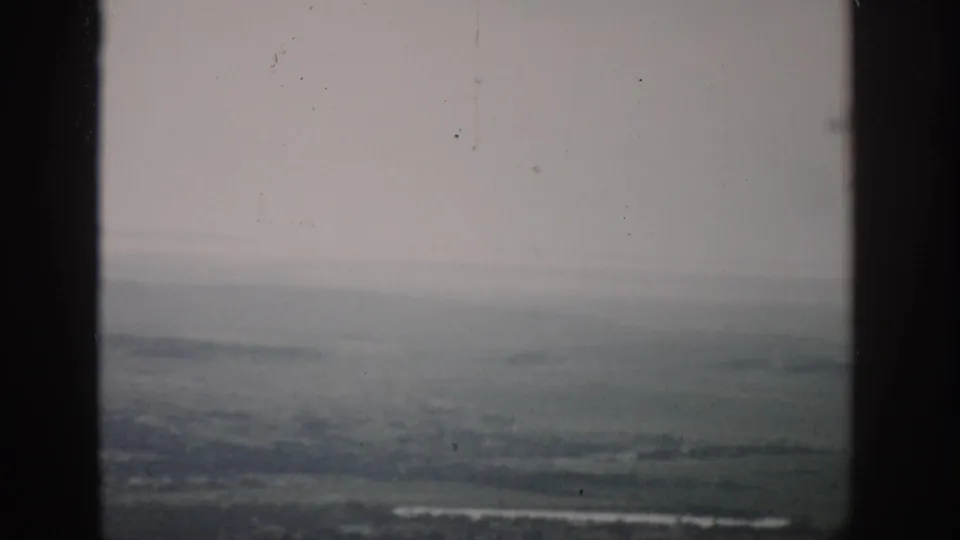 A faded 1959 Colorado airplane-window frame shows a pale horizon, distant terrain, and light-toned strips below.