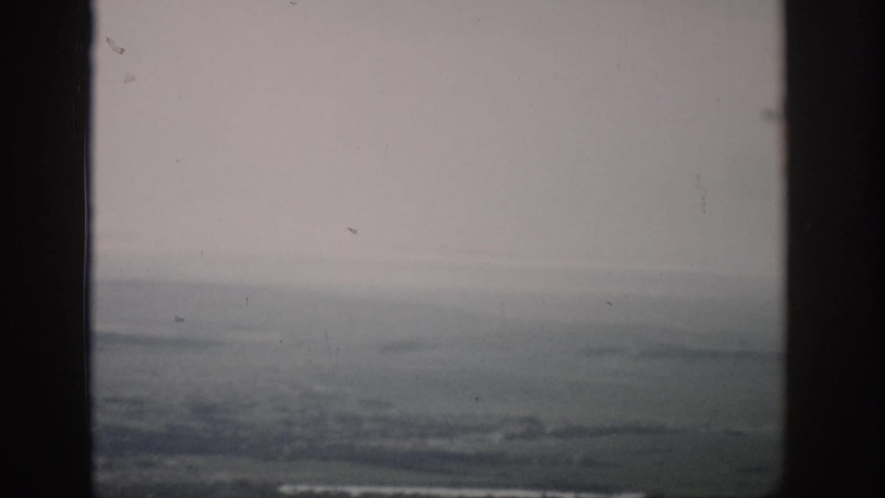 1959 Colorado 8mm frame showing distant flat land and haze through a dark window frame.
