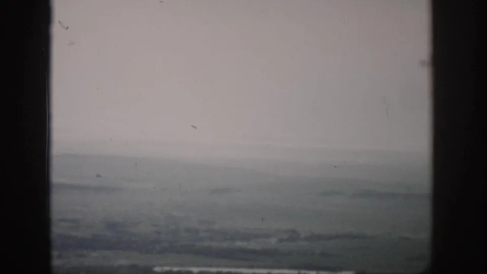 1959 Colorado 8mm frame showing distant flat land and haze through a dark window frame.