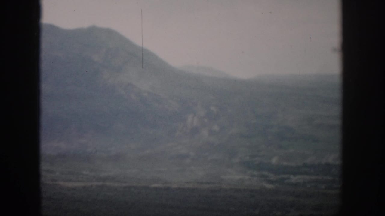 1959 Colorado travel footage showing a soft, hazy mountain and valley view through dark framing edges.