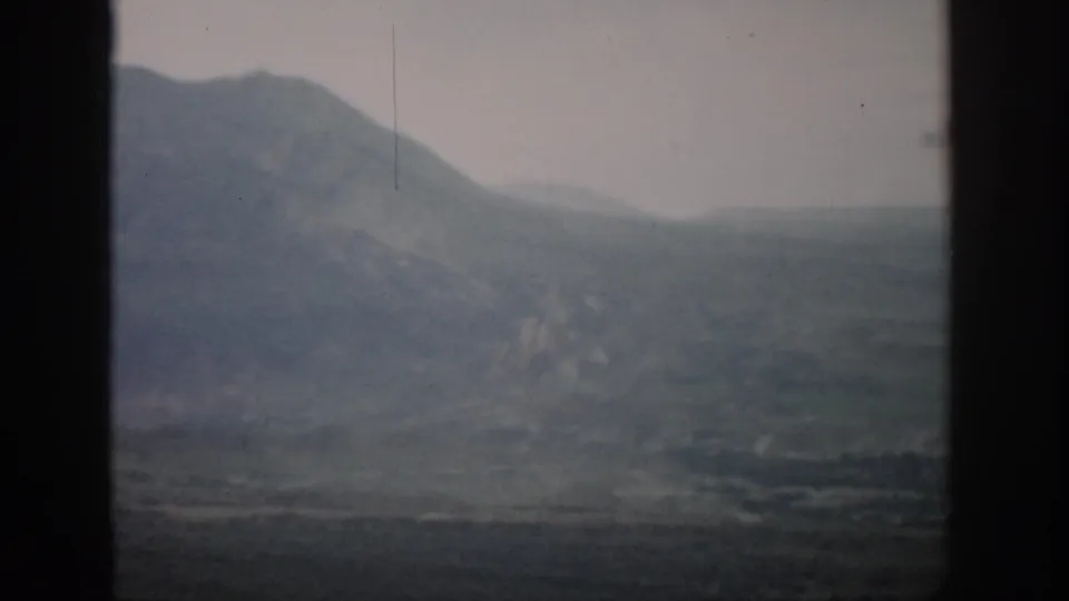 1959 Colorado travel footage showing a soft, hazy mountain and valley view through dark framing edges.