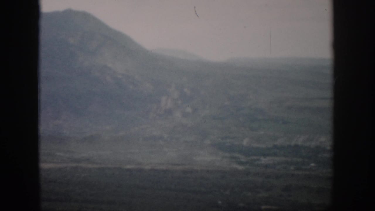 Soft 8mm view of Colorado mountain terrain and distant valley, divided by dark vertical framing.
