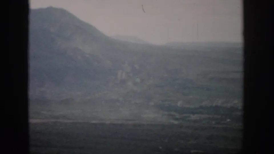 Soft 8mm view of Colorado mountain terrain and distant valley, divided by dark vertical framing.