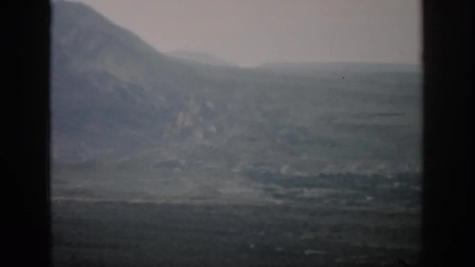 Hazy Colorado mountain landscape in muted color, with dark film or window edges crossing the frame.
