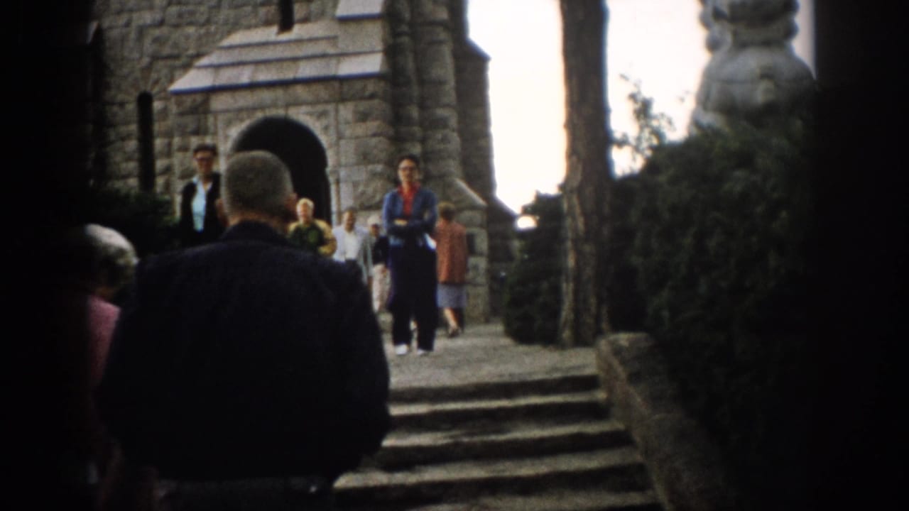 Adults walk toward stone steps and an arched church entrance.