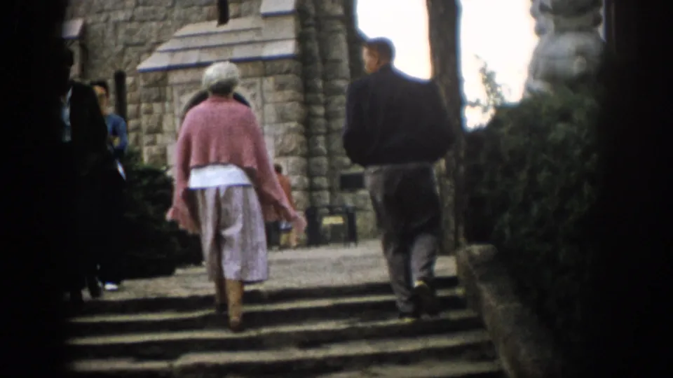 Near the end of the clip, the couple continues up the steps beside shrubs and stone church architecture in Colorado.