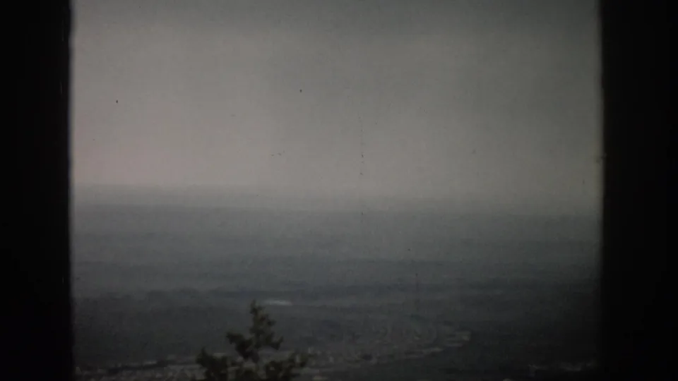 1959 Colorado 8mm view over a hazy valley landscape, framed by dark vertical edges and softened by overcast light.