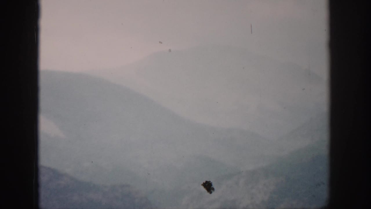 1959 Colorado 8mm frame showing layered, fog-covered mountain ridges through a dark window frame.