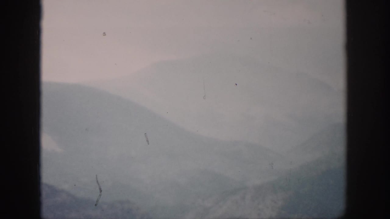Distant fog-covered mountains divided by a vertical window bar.