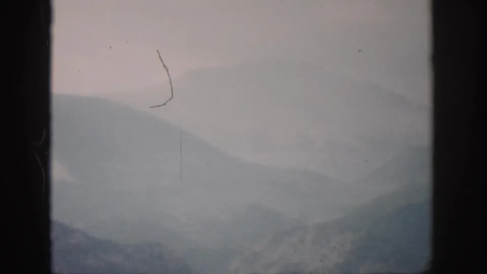 1959 Colorado 8mm view of muted mountain slopes and fog through a dark lower window pane.