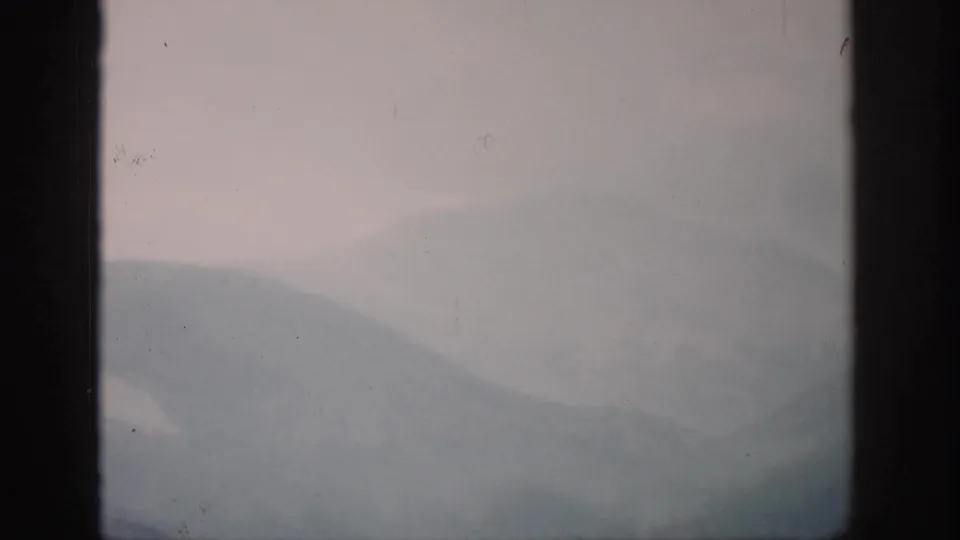 1959 Colorado frame showing hazy ridgelines fading into gray fog behind a dark window frame.