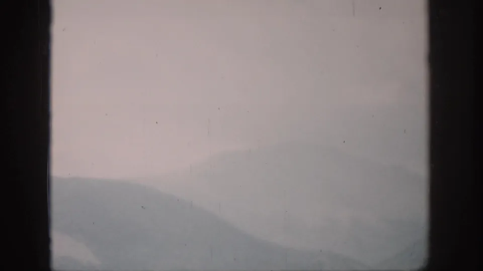 1959 Colorado 8mm frame showing hazy mountain ridges at dawn through dark vertical window framing.