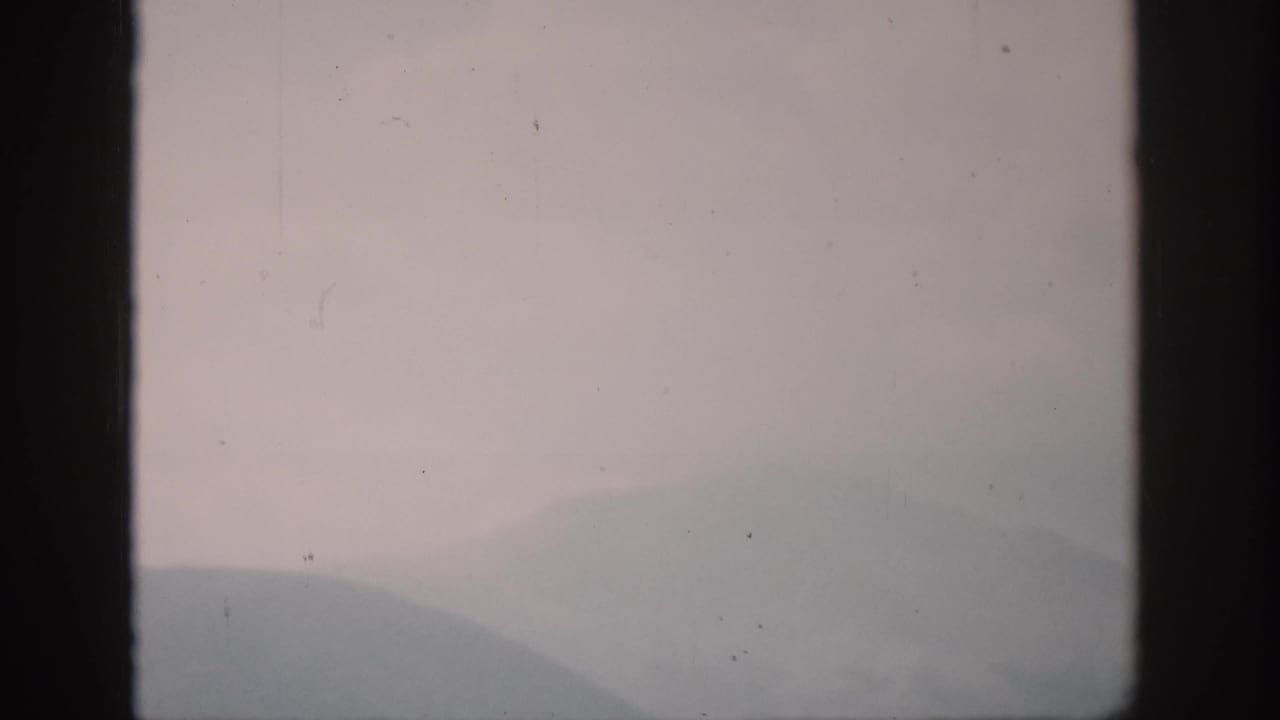 Muted mountain silhouette and haze divided by a dark vertical frame.