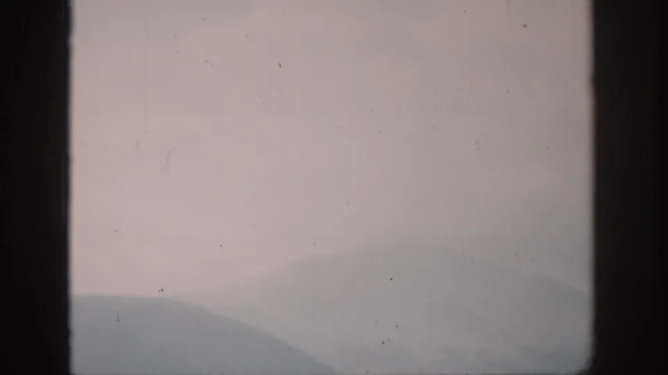 1959 Colorado home-movie view of distant hazy mountains and pale dawn light behind a dark window mullion.