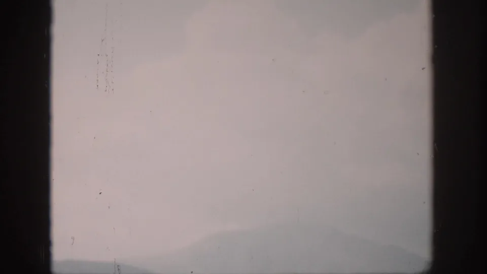 1959 Colorado 8mm frame showing faint mountain forms fading into mist under a cold dawn sky.
