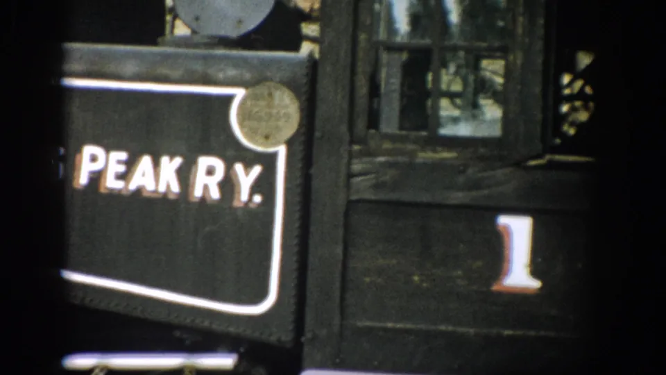 1959 Colorado 8mm frame showing a close-up of a black railway car panel marked Peak Ry. with the number 1 beside it.