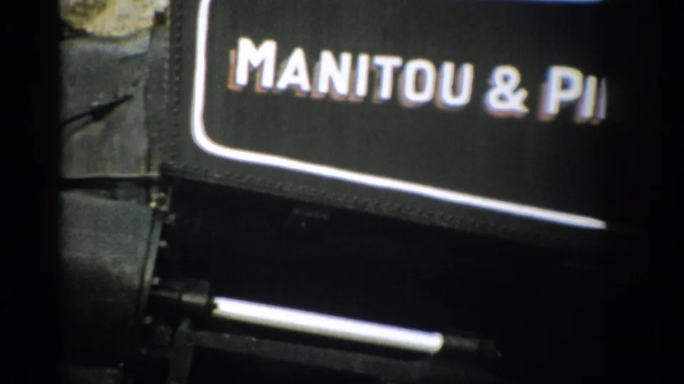 1959 Colorado 8mm frame showing part of the Manitou & Pike's Peak Railway name on a black train-car sign.