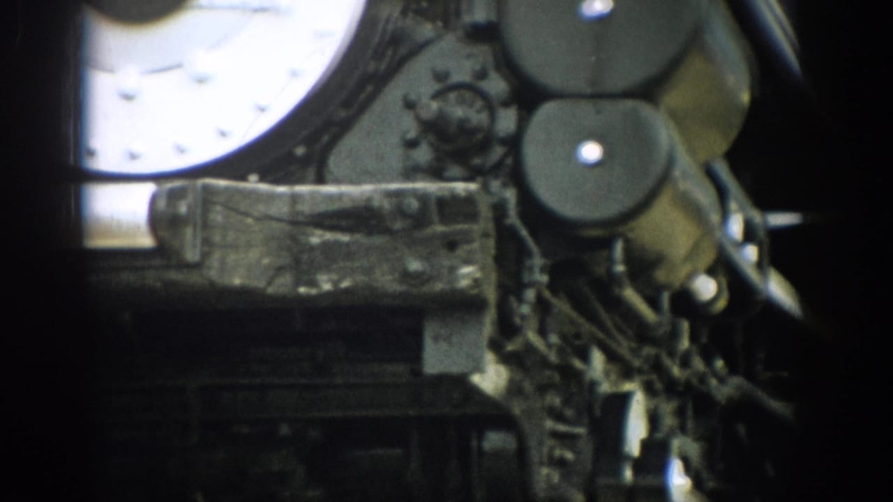 Close locomotive machinery with round plates, rods, and worn metal surfaces.