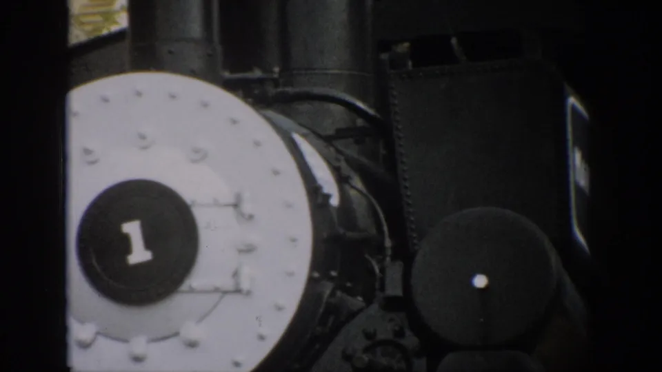 1959 Colorado 8mm frame of a black steam locomotive front, centered on the white plate with a dark number 1 badge.