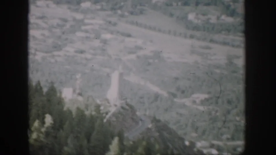 1959 Colorado home-movie frame of a valley seen from a moving train, bordered by dark frame edges and softened by motion.