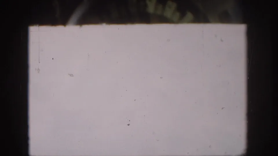 Overexposed 8mm frame with a pale field, visible dust specks, scratches, and dark contact-sheet borders.