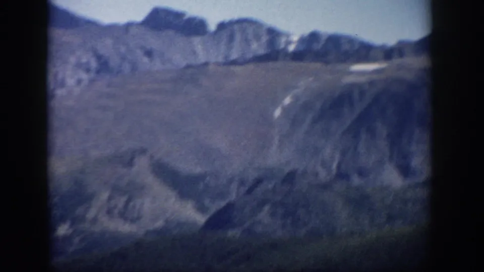 1959 Colorado 8mm view of a mountain basin with soft ridges, muted slopes, and a small pale snow patch.