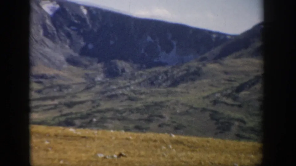 1959 Colorado home-movie frame showing a distant mountain ridge and broad alpine terrain along Trail Ridge Road.