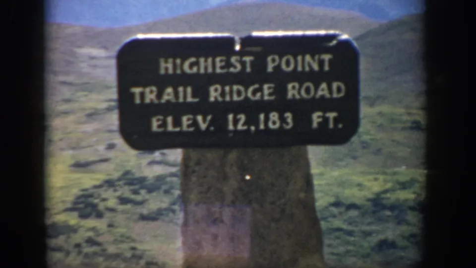 Final 1959 Colorado frame showing the Trail Ridge Road elevation marker slightly off-center against open alpine hills.