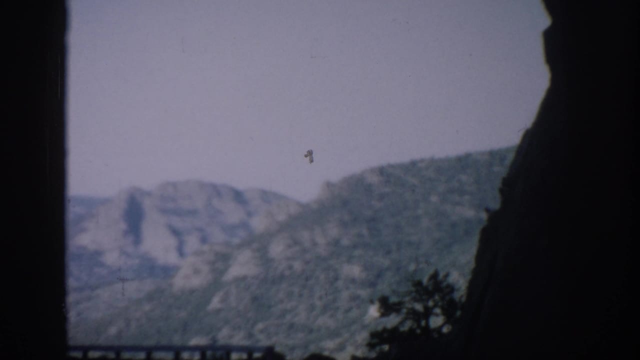 Mountain ridges seen through a dark helicopter window frame.