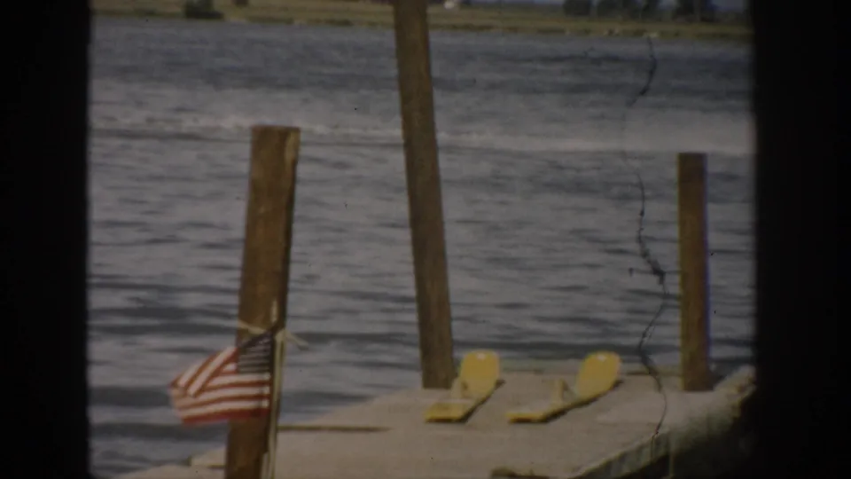 Foreground dock with an American flag, yellow dock items, and vertical posts, with the Colorado lake visible behind them.