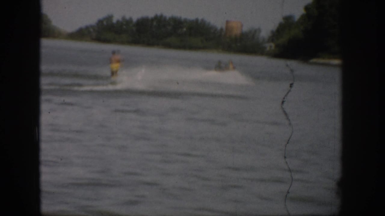 A water skier appears mid-lake in the 1959 Colorado footage, leaving spray behind as the distant shore stays soft in focus.