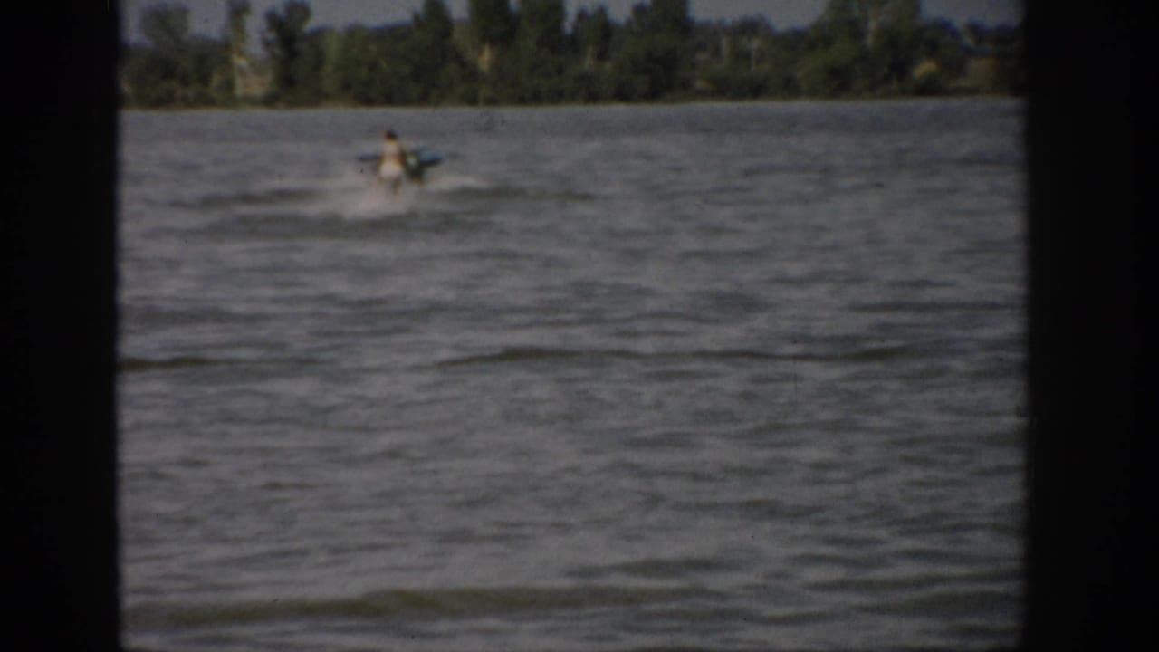 A woman appears to water ski behind a motorboat on a windy Colorado lake in 1959 color 8mm footage.