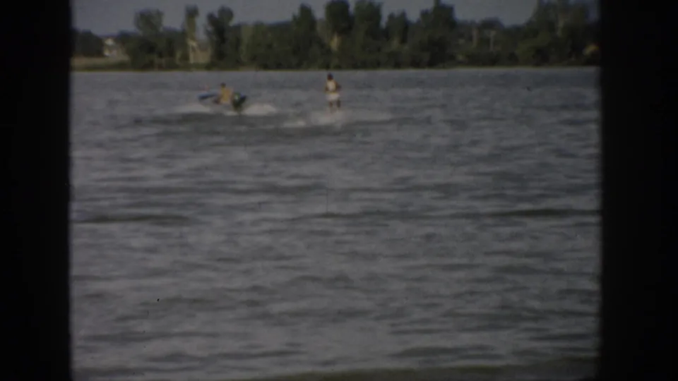 1959 Colorado lake scene with a motorboat towing a woman water skier across choppy water in home-movie footage.