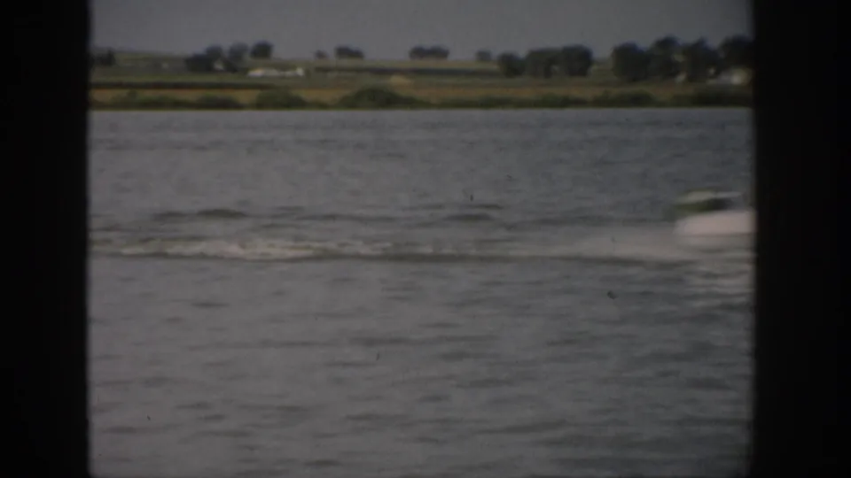 1959 Colorado water-sport moment with a fast-moving craft or skier blurred near the foreground and a long wake across the lake.