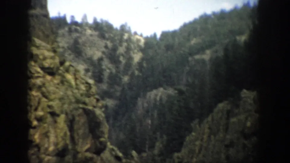 Colorado 8mm travel frame showing rocky outcrops, evergreen-covered hillsides, and soft archival color.