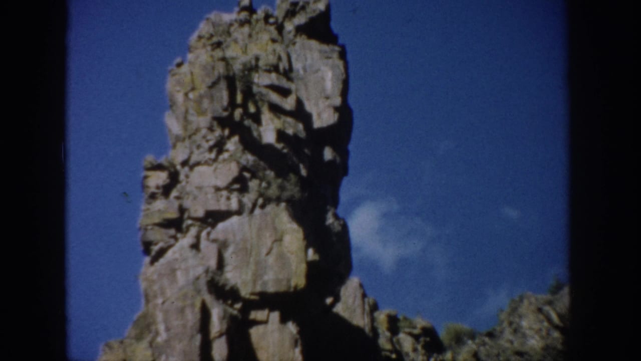Closer view of a cracked rock tower below a deep blue sky.